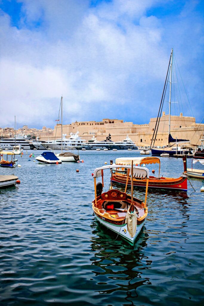 Thuyền du lịch ở cảng Valletta di chuyển trên làn nước màu xanh ngọc Địa Trung Hải